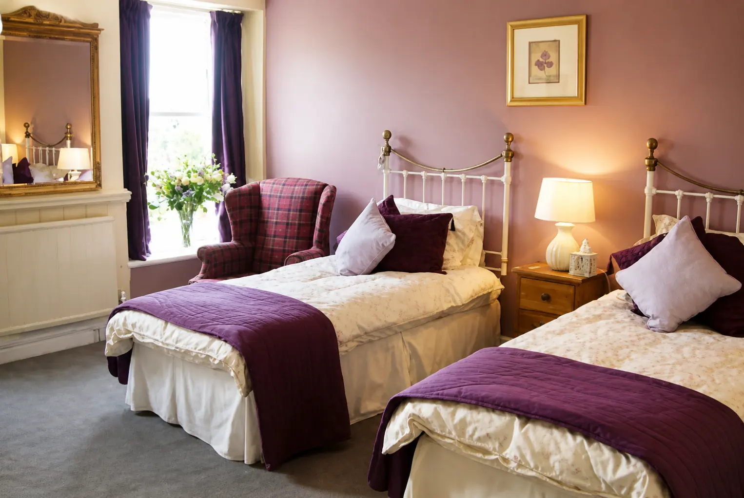 Twin room with two iron-framed beds and an armchair by the window